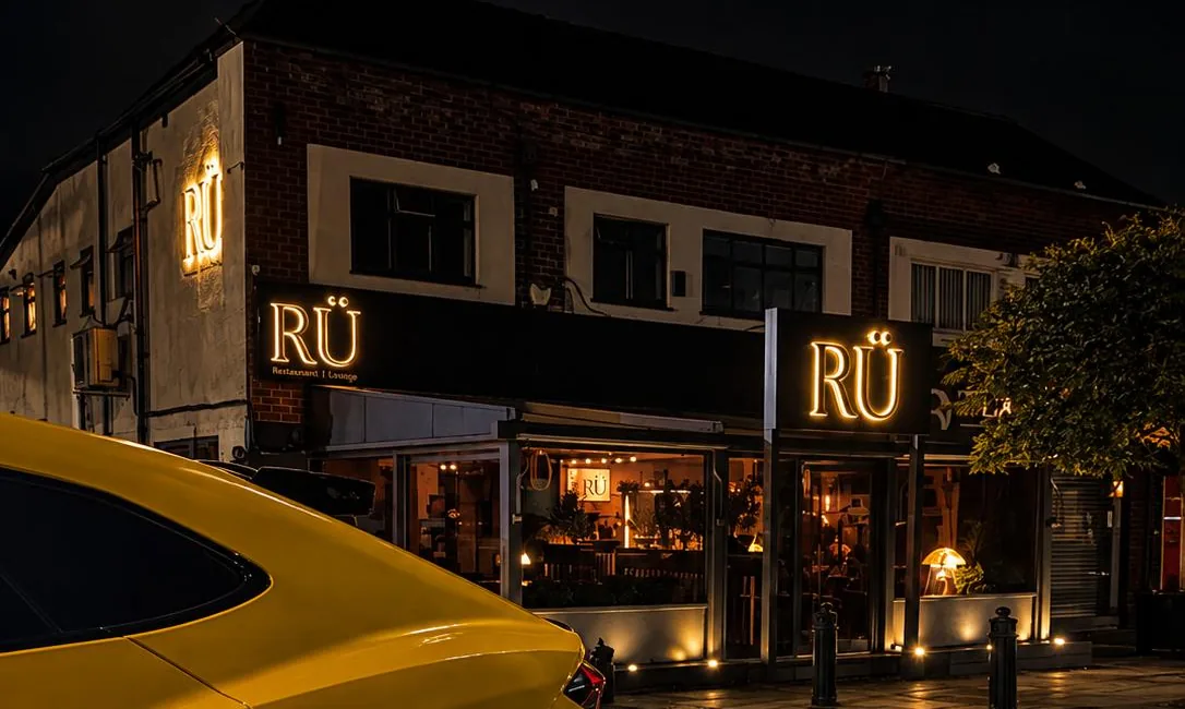 The RÜ shopfront and signs on Station Road at night