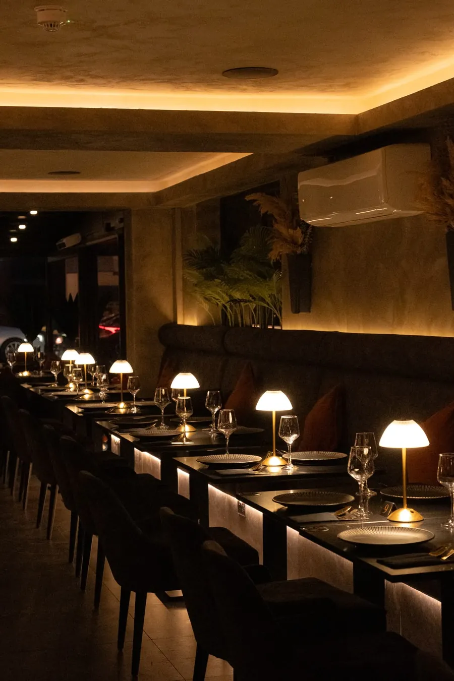 The long banquette lit by a row of table lamps