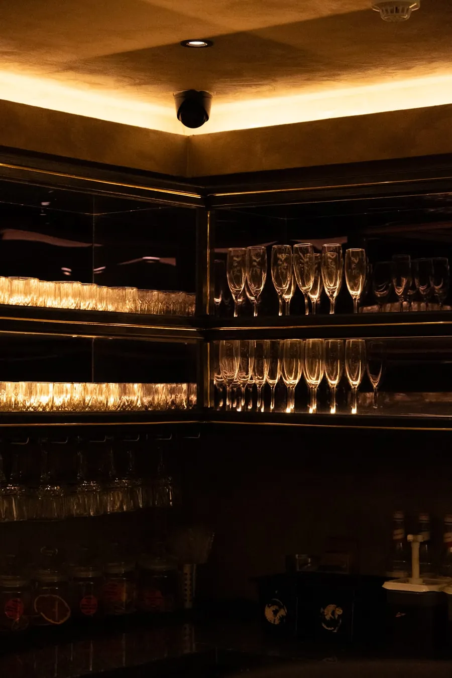 Lit shelves of glassware behind the bar