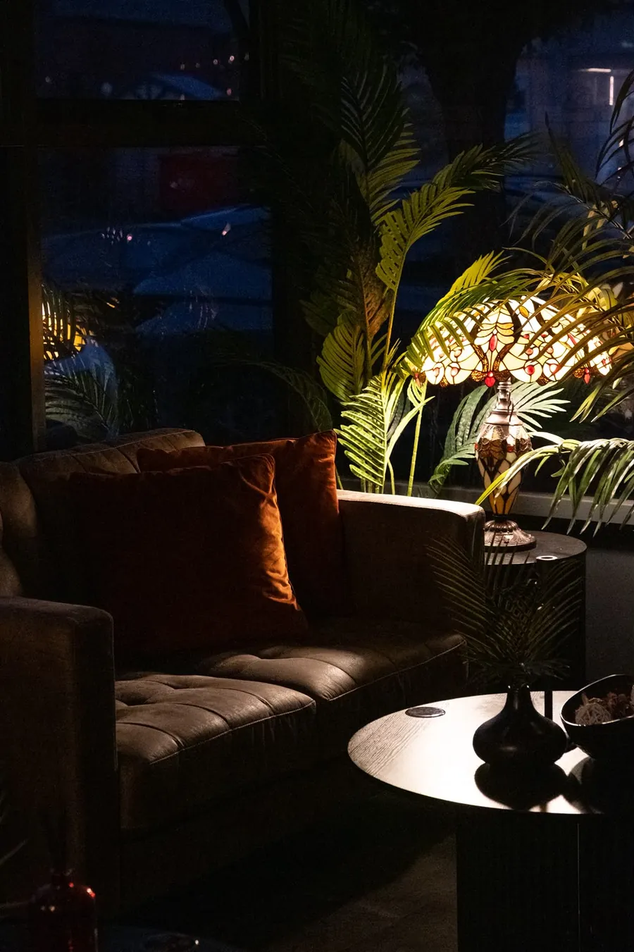 Deep velvet sofa and marble tables beside the palms